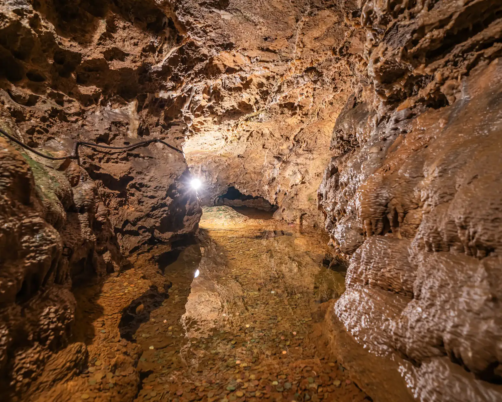 Gang mit Wasserfläche und Spiegelung, am Ende Licht