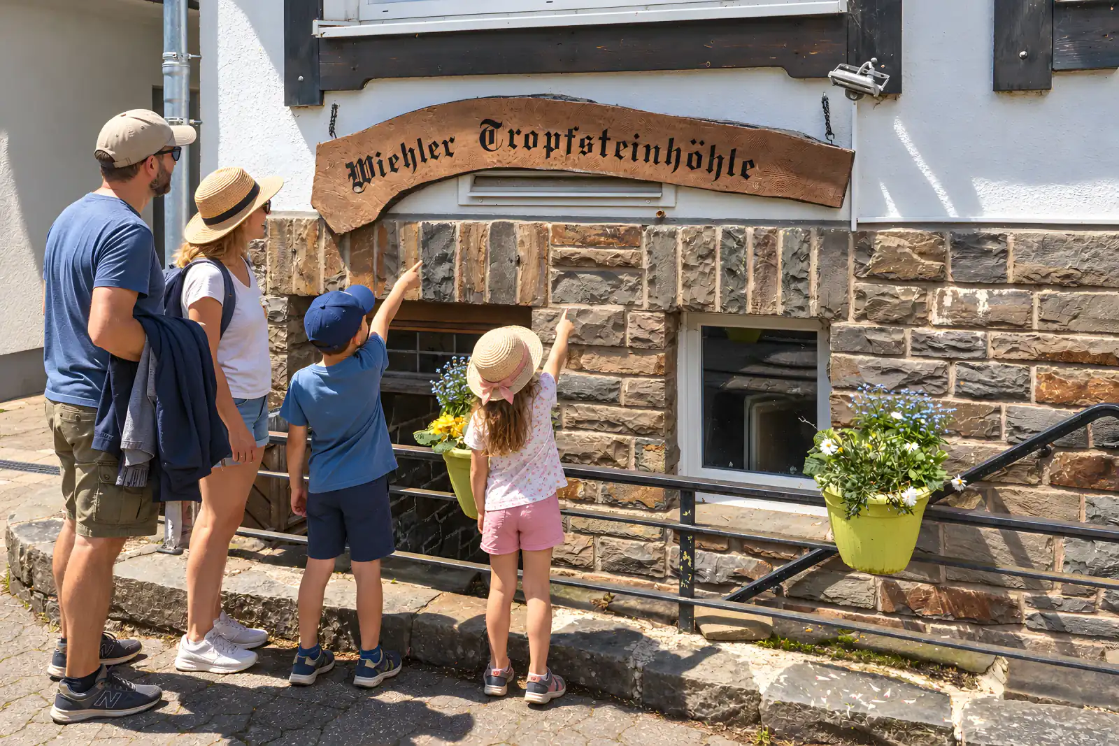Familie am Höhleneingang an einem heißen Sommertag, Jacken über dem Arm