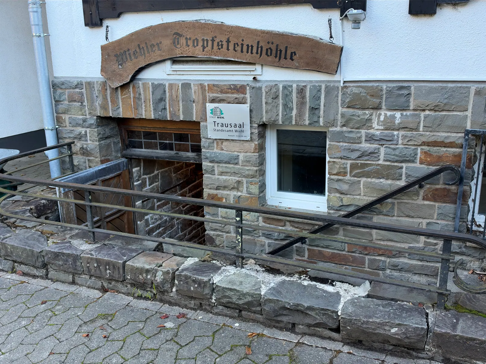 Eingang der Wiehler Tropfsteinhöhle mit Holzschild über der Treppe