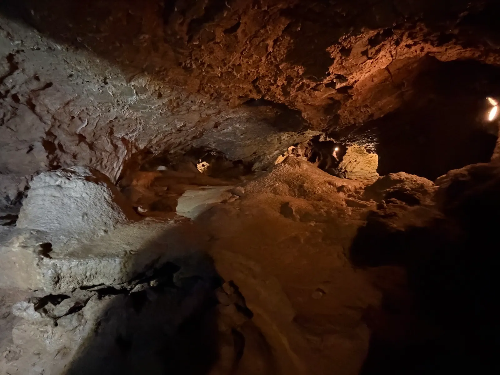 Rötlich beleuchtete Halle mit Lampen in der Tropfsteinhöhle