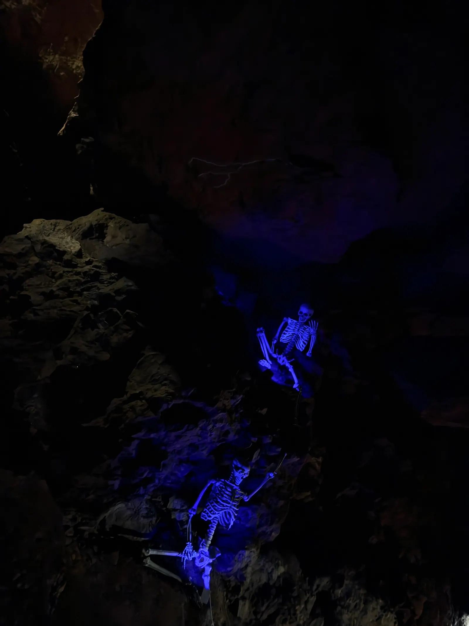 Skelette im blauen Schwarzlicht in der dunklen Höhle