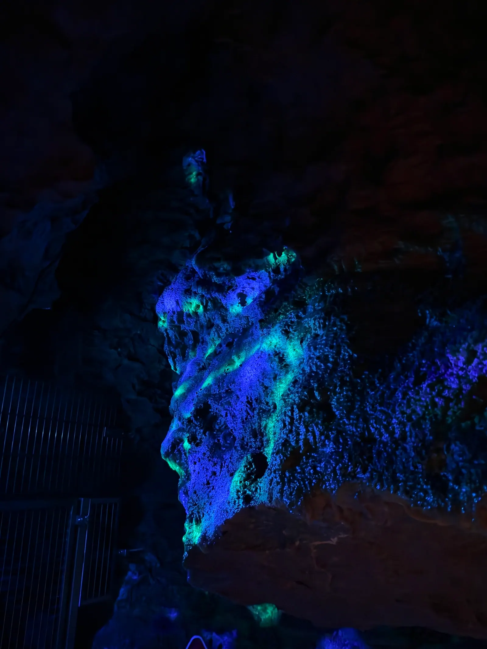 Grün und blau im UV-Licht leuchtende Felswand in der Höhle, Halloween